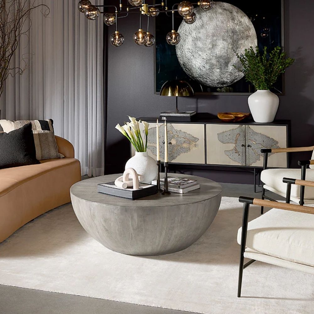 Small round concrete coffee table with a curved bowl-like base and smooth grey finish.