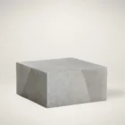 Square concrete coffee table with angular crack-inspired detail and softly weathered stone texture.