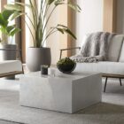 Square concrete coffee table with angular crack-inspired detail and softly weathered stone texture.