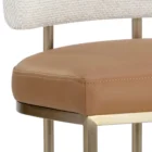 A modern Larissa Stool featuring a warm caramel leather seat, curved white boucle backrest, and slim brushed brass metal frame.