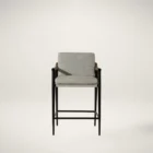 Meadow Counter Stool highlighting the curved backrest, textured upholstery, and sleek black frame with integrated wooden armrests.