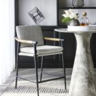 Meadow Counter Stool highlighting the curved backrest, textured upholstery, and sleek black frame with integrated wooden armrests.
