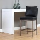 Paige Counter Stool featuring a black faux leather upholstered seat and loose-style back cushion, set on a brushed metal frame with footrest