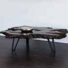 Live-edge sculptural coffee table crafted from dark natural teak wood with organic curves and black angular legs.