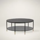 Round black coffee table with slim metal frame, lower glass shelf, and gold-dipped leg tips.