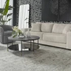 Round black coffee table with slim metal frame, lower glass shelf, and gold-dipped leg tips.