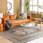 A warm-toned, vintage-inspired area rug with a distressed Persian design featuring muted browns, soft blues, and ivory accents, styled in various living spaces.