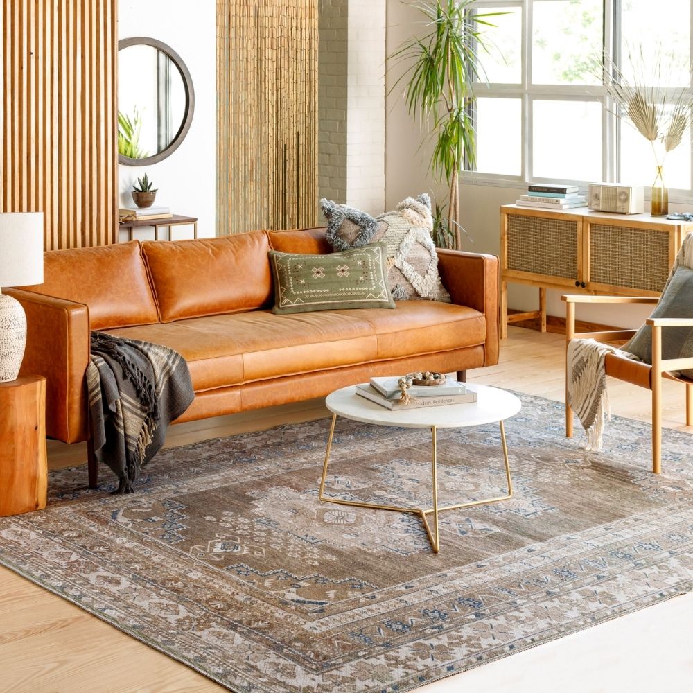 A warm-toned, vintage-inspired area rug with a distressed Persian design featuring muted browns, soft blues, and ivory accents, styled in various living spaces.