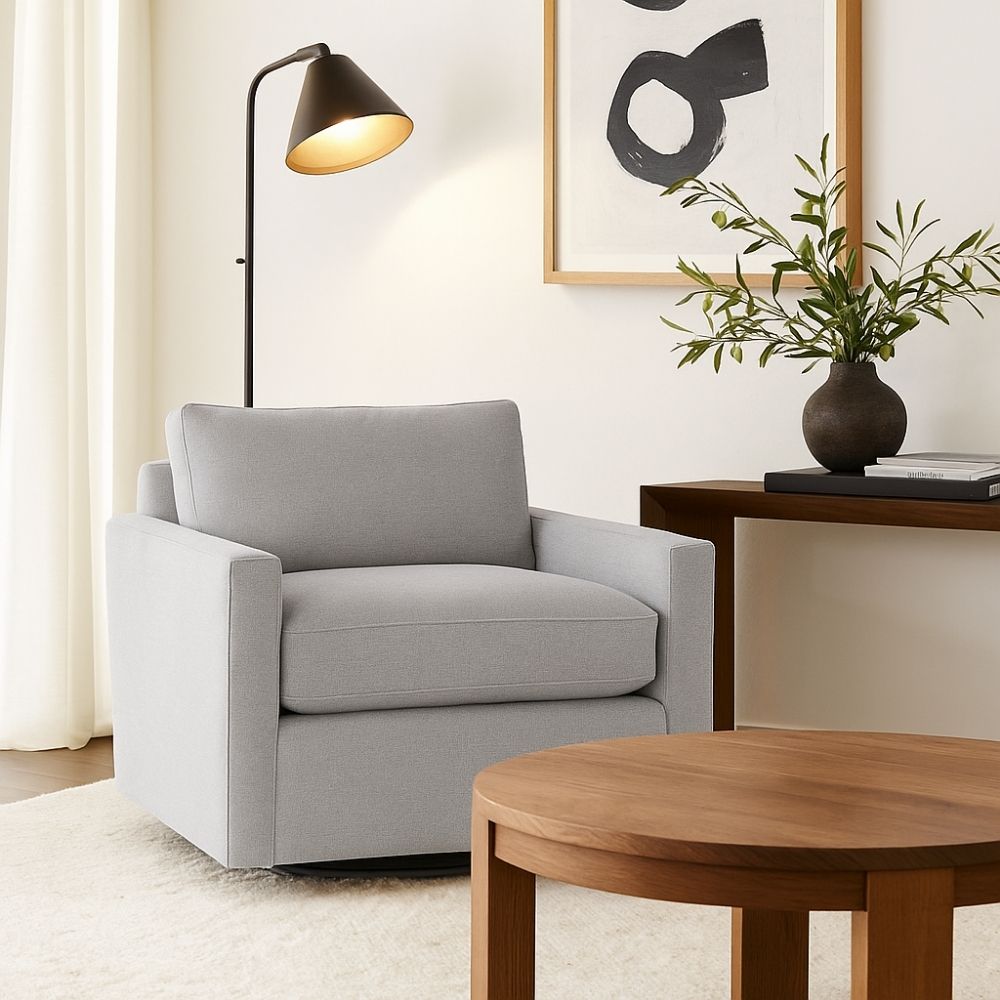 A modern swivel chair with clean lines, upholstered in a soft off-white fabric, featuring a boxy silhouette and low-profile base.