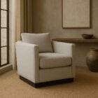 Modern ivory swivel chair with boxy arms, plush cushions, and a sleek black plinth base