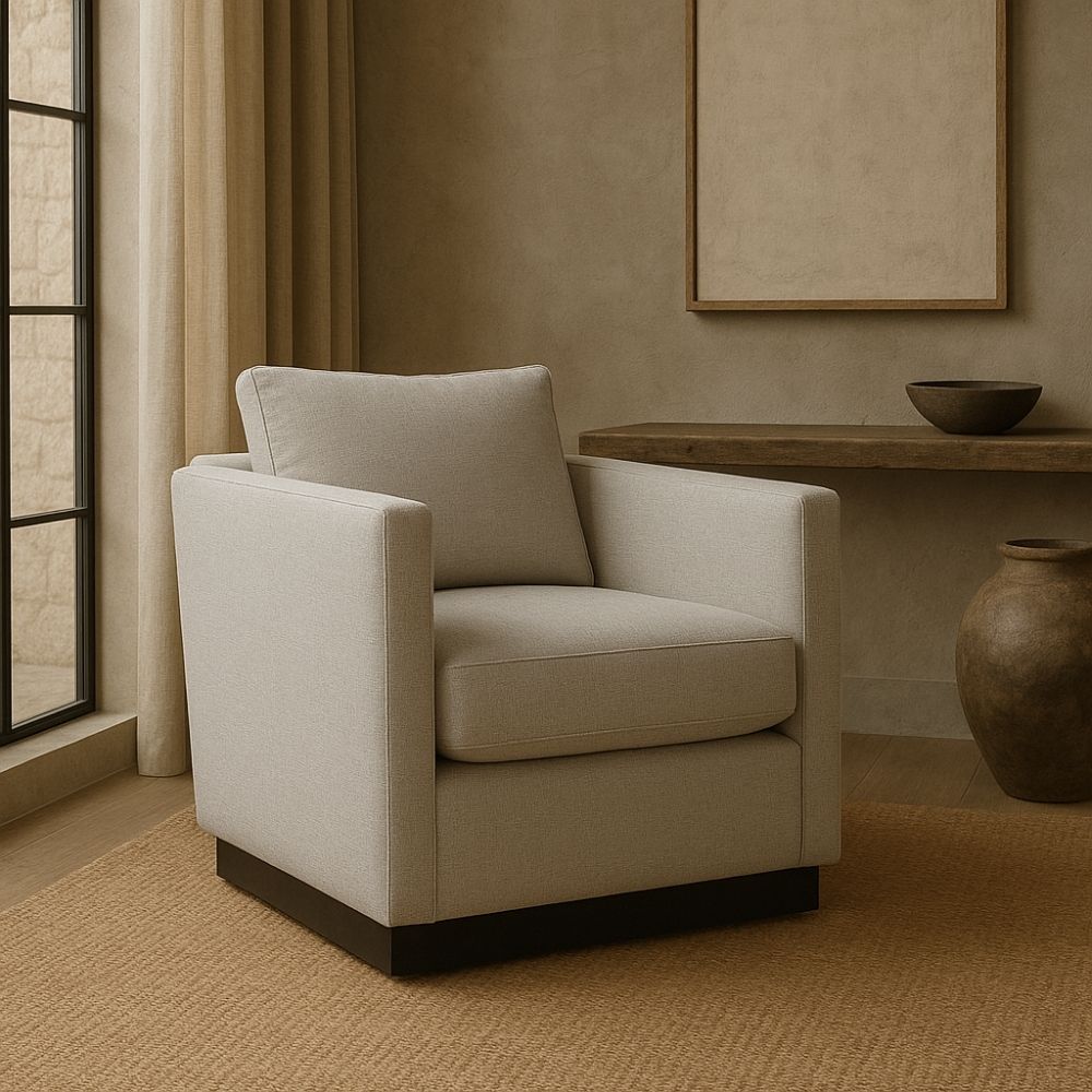 Modern ivory swivel chair with boxy arms, plush cushions, and a sleek black plinth base