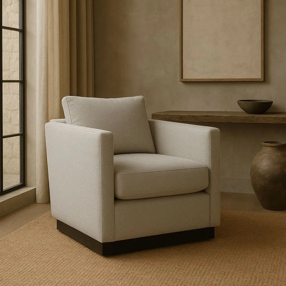 Modern ivory swivel chair with boxy arms, plush cushions, and a sleek black plinth base