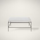 Rectangular white cocktail table with a raised-edge surface and slim black metal frame base.