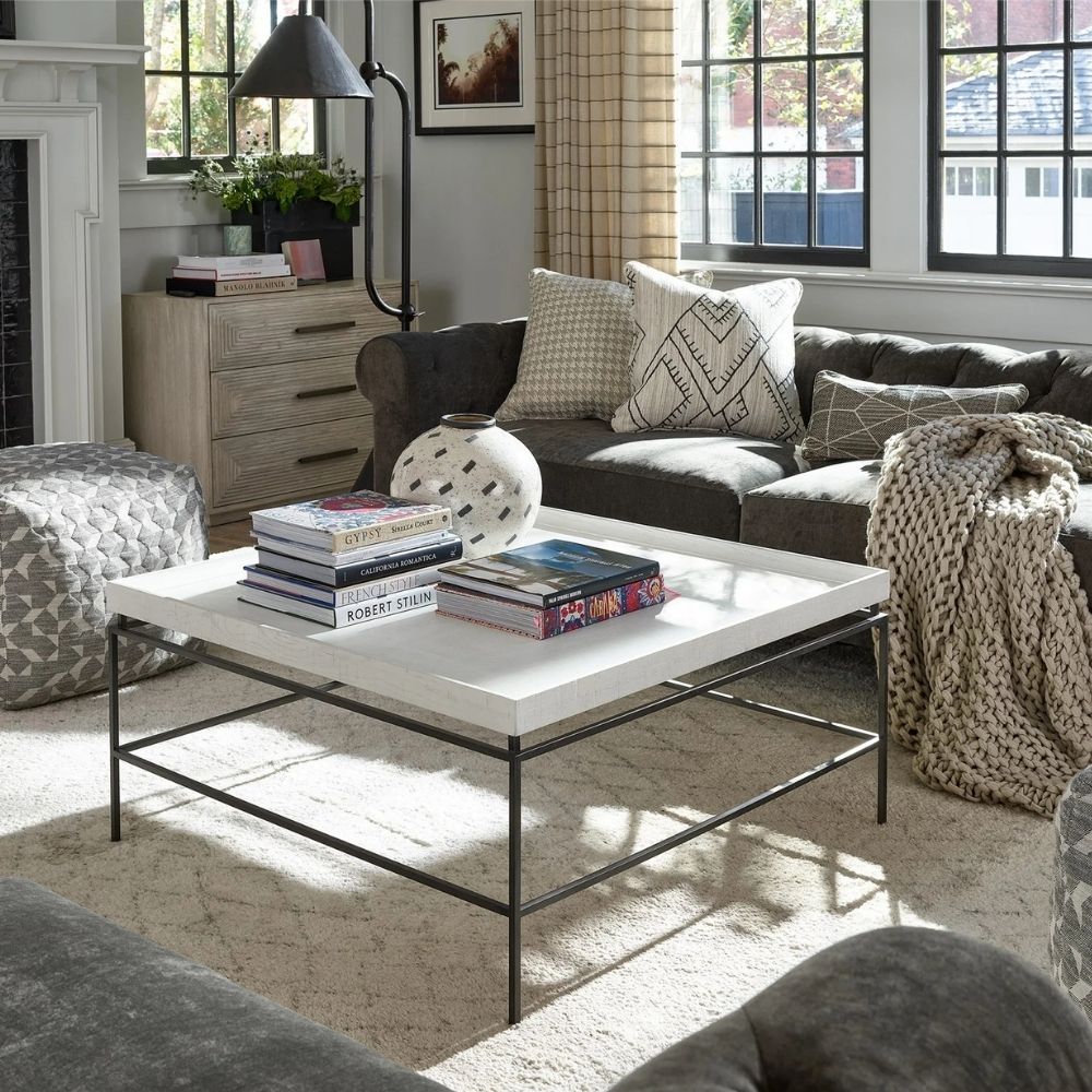 Rectangular white cocktail table with a raised-edge surface and slim black metal frame base.