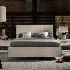 A modern Huston Nightstand featuring a sleek open-frame design with a single drawer and lower shelf in a light wood finish, styled beside a contemporary bed.