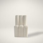 A modern armless side chair in soft ivory bouclé with deep vertical channelling on the seat and back, featuring a fully upholstered silhouette.