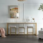 Elegant console table with a white top and brushed gold frame, paired with three coordinating upholstered stools.