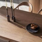 A minimalist rectangular wood dining table with soft-rounded edges and natural grain finish, shown in a studio-style background.