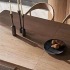 A minimalist rectangular wood dining table with soft-rounded edges and natural grain finish, shown in a studio-style background.