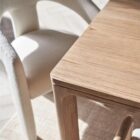 A minimalist rectangular wood dining table with soft-rounded edges and natural grain finish, shown in a studio-style background.