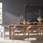 A minimalist rectangular wood dining table with soft-rounded edges and natural grain finish, shown in a studio-style background.