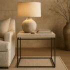 Minimalist end table with a white textured top and thin matte black metal frame.