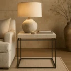Minimalist end table with a white textured top and thin matte black metal frame.