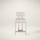 A modern counter stool featuring a soft upholstered back and seat in a neutral woven fabric, supported by a sleek polished metal frame with a footrest.