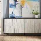 A long, low-profile entertainment console with a textured light wood front and contrasting black frame and top.