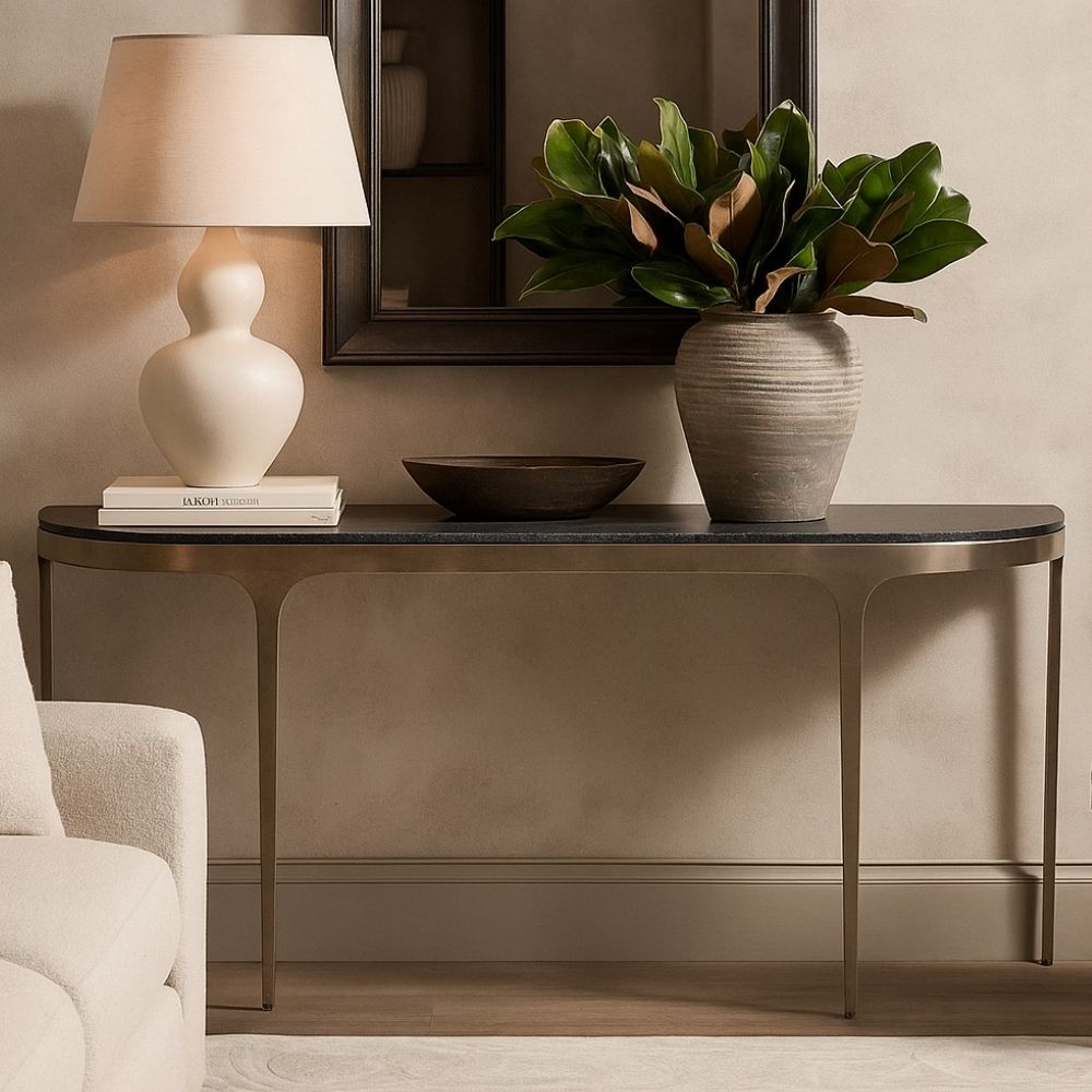 Modern console table with a sleek black stone top and elegant, tapered brass legs that curve into a rounded-edge profile.