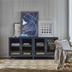 A sleek, short black metal kitchen cabinet with two glass doors, gold-tone handles, and a minimalist open base.