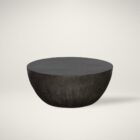 Round black coffee table with a smooth, matte finish and softly curved base in a minimalist drum silhouette
