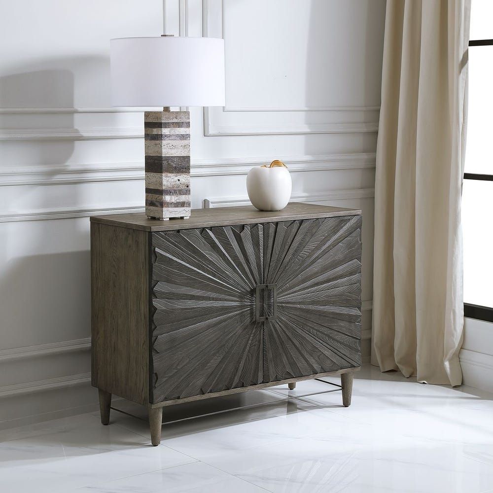 Dark wood two-door cabinet with sunburst carved front panel and modern rectangular handles.