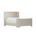 The Tilburg Bed featuring a high, fully upholstered headboard and footboard in a soft neutral fabric with a clean, curved silhouette.