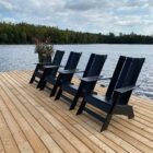 Modern black Adirondack-style outdoor chair with angled slats and wide armrests, set against a neutral background.