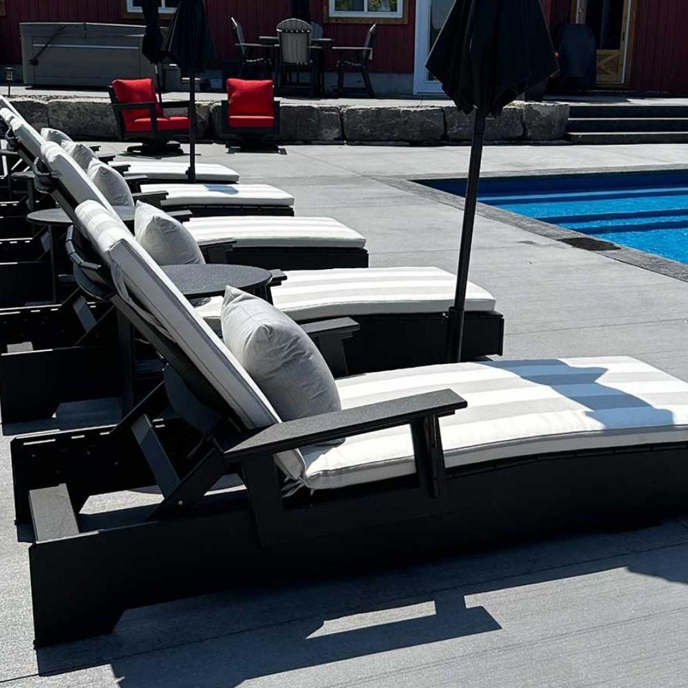 Modern black outdoor lounge chair with adjustable backrest and wide armrests, shown in a minimalist studio setting.