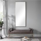A modern full-length rectangular mirror with a slim metallic frame and a minimalist design.