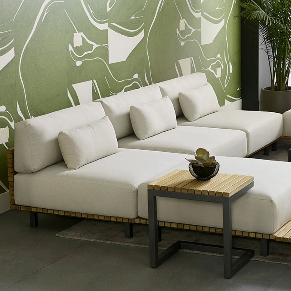 Contemporary outdoor armless lounge chair with white cushions, natural wood base, and black metal legs.