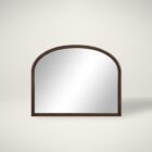 A sleek oval-shaped Renwell Kindra Mirror with a thin, minimal metal frame in a warm brass finish, mounted on a light-toned wall.