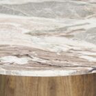 Round dining table with a polished pink marble top and smooth wood pedestal base.