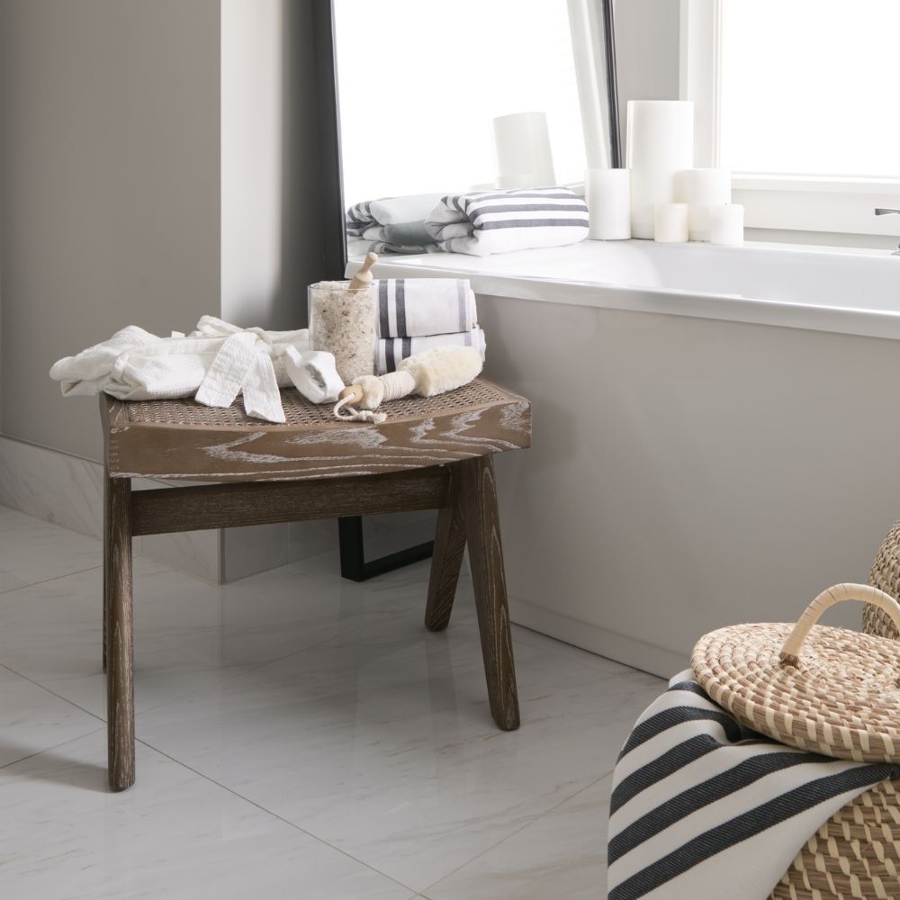 Low wood accent stool with woven cane seat and sculpted legs in a weathered oak finish.