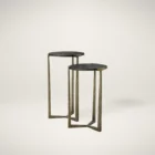 Pair of round nesting accent tables with charcoal wood tops and antique brass metal frames.