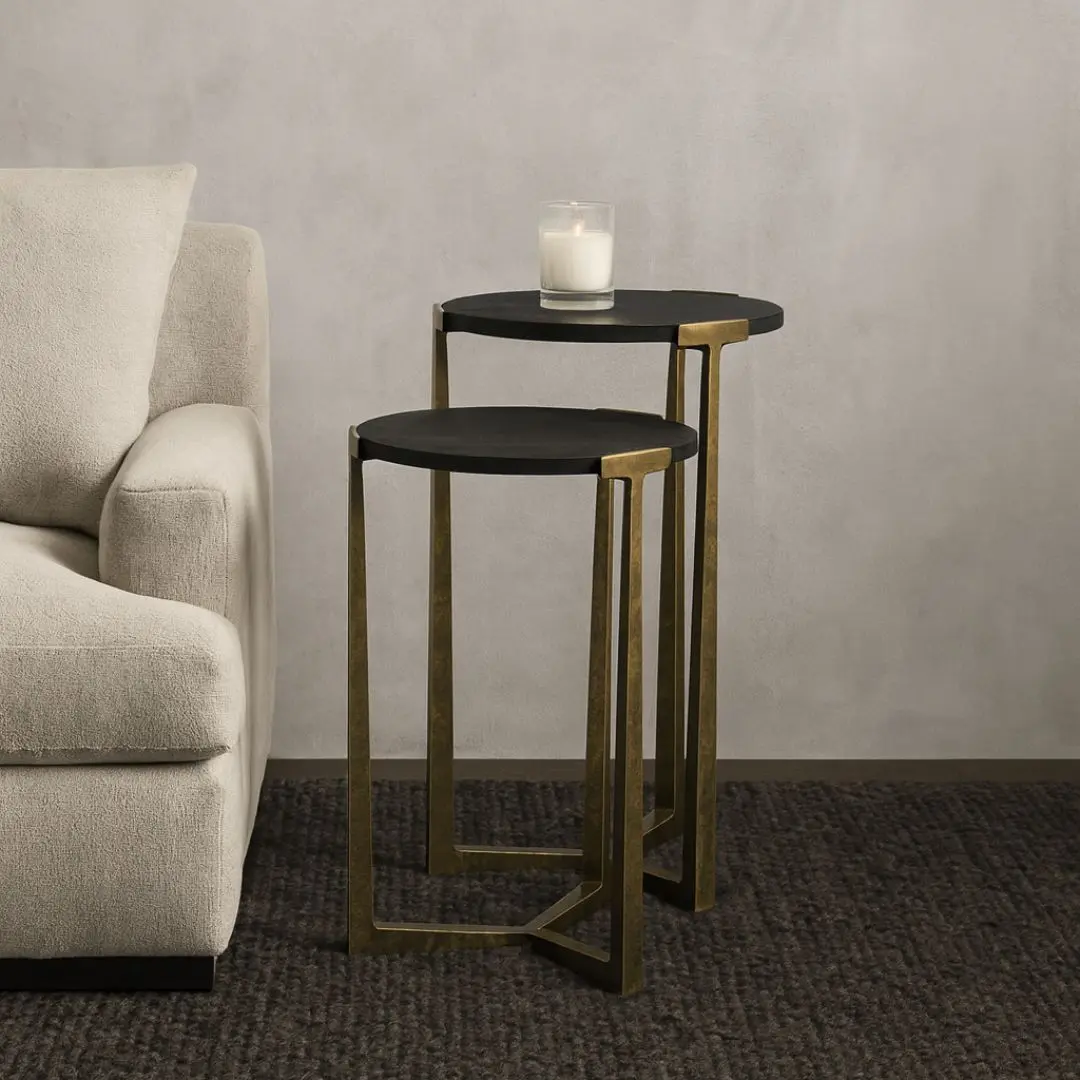 Pair of round nesting accent tables with charcoal wood tops and antique brass metal frames.