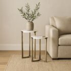 Set of two round white marble nesting tables with antique brass metal bases.