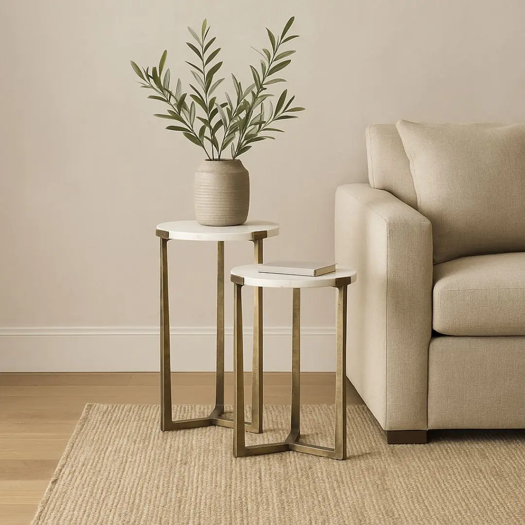 Set of two round white marble nesting tables with antique brass metal bases.