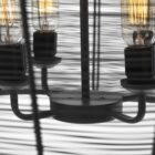 Black metal wire-frame chandelier with a curved silhouette and exposed four-bulb candelabra fixture inside.