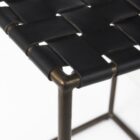 Minimalist counter-height stool with dark woven leather seat and slender black metal frame.