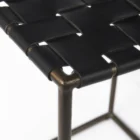 Minimalist counter-height stool with dark woven leather seat and slender black metal frame.