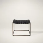 Modern ottoman with black woven leather seat and brass-finished metal frame.