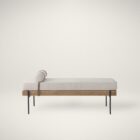 Mercana Colburne bench with beige cushion, natural wood base, and black metal legs, featuring a strapped bolster pillow.